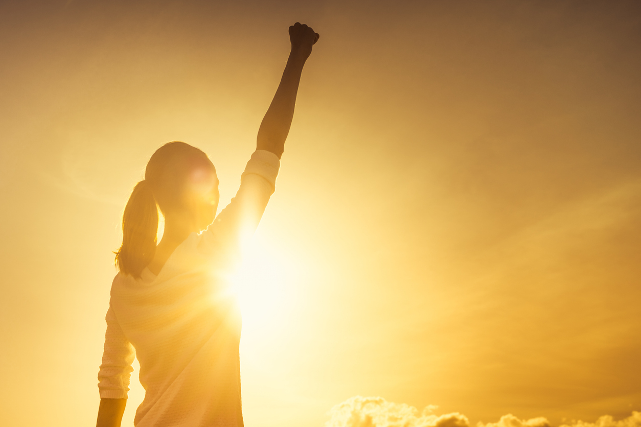Woman with fist in the air at sunset.