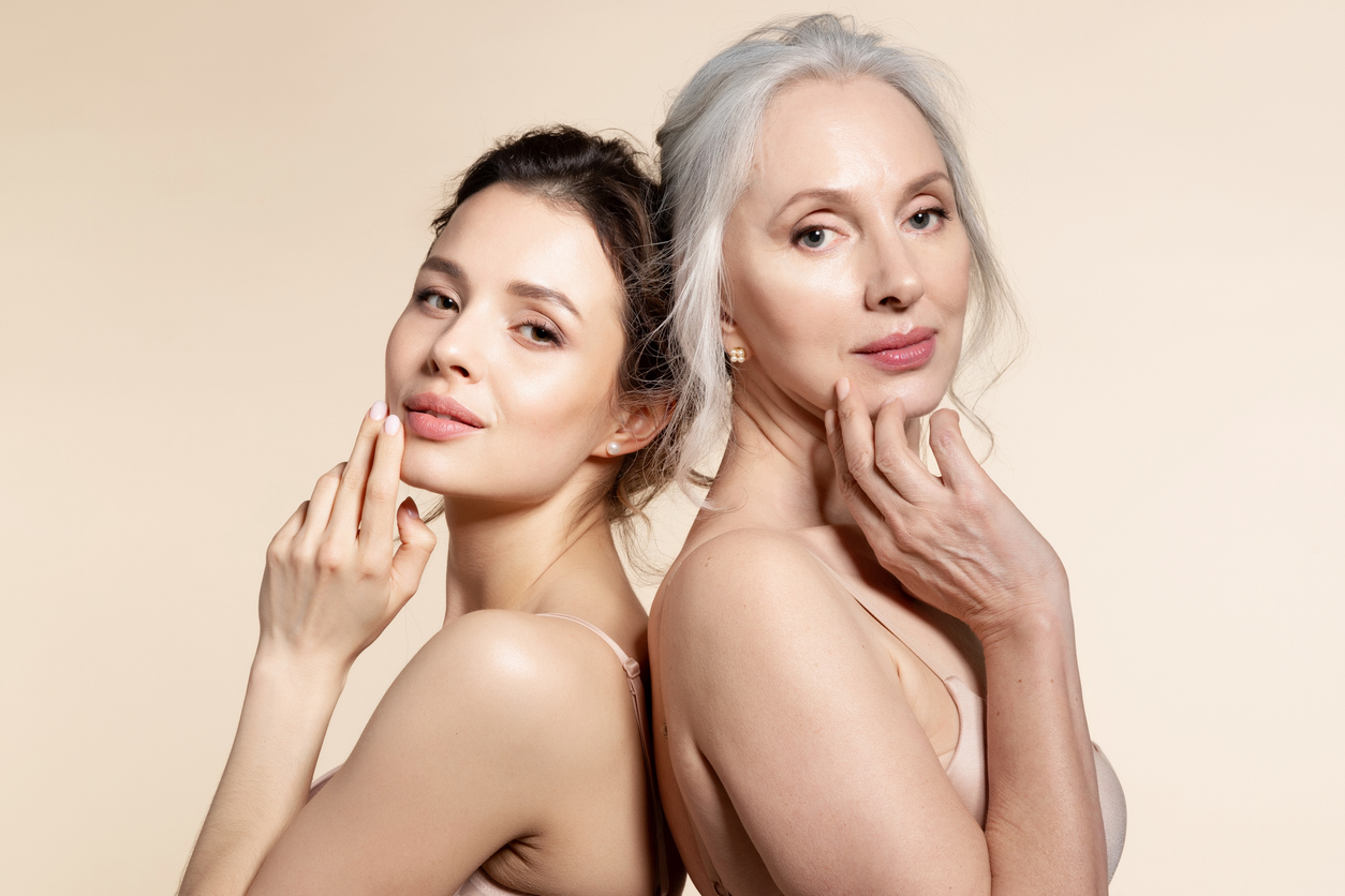 Elderly and young women with smooth skin and natural makeup standing back-to-back. Thinking, planning, dreaming